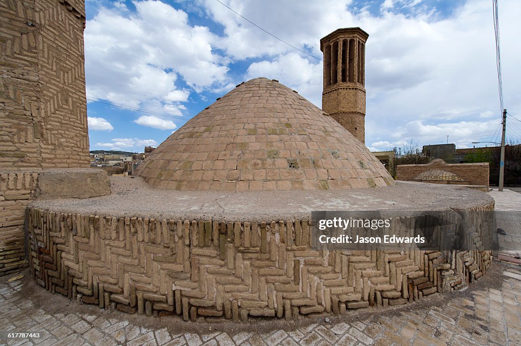 The dome ceiling of an ancient cistern and a windcatcher in a village.