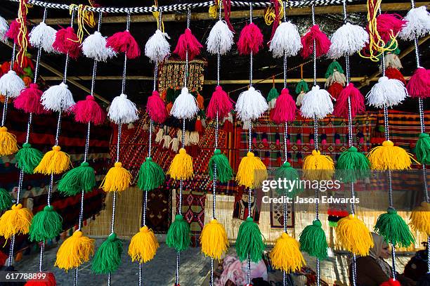 colourful tassles hanging from a bedouin stall in a market celebrating nowruz iranian new year. - nowruz stock-fotos und bilder