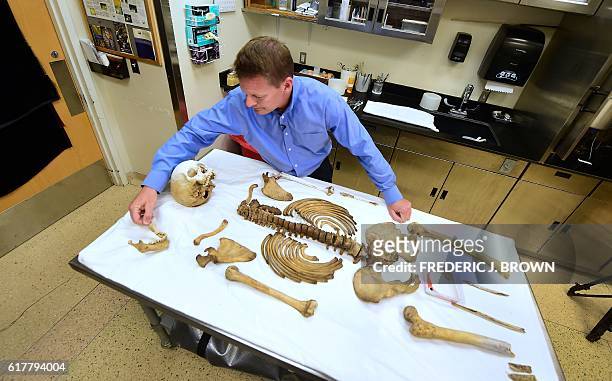 Pima County medical examiner Dr. Gregory Hess stands over a table with the laid out skeletal remains of a person who died trying to cross the...