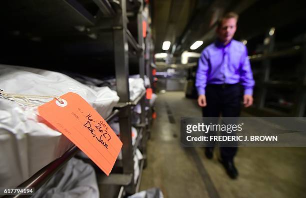 Pima County medical examiner Dr. Gregory Hess walks through the morgue filled with body bags of the dead, including some of those who died trying to...