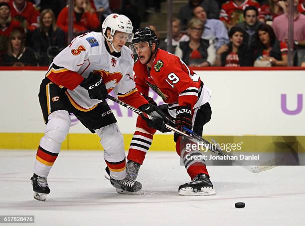 Jyrki Jokipakka of the Calgary Flames knocks the puck away from Jonathan Toews of the Chicago Blackhawks at the United Center on October 24, 2016 in...
