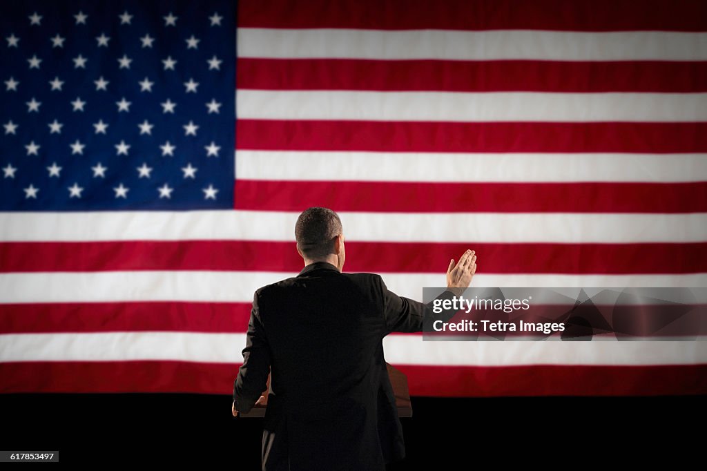 Politician giving speech with American flag in background