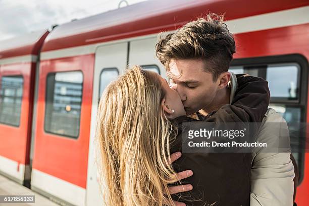 "young couple kissing at train station, munich, bavaria, germany" - couple in a train stock pictures, royalty-free photos & images