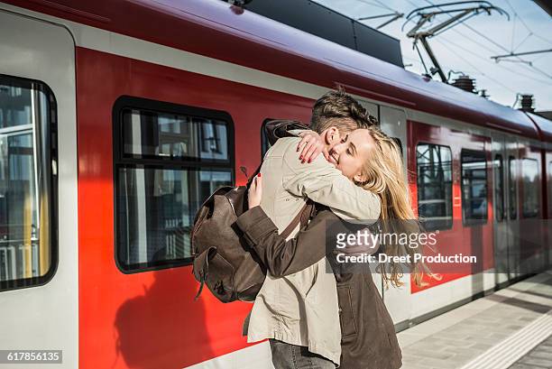 "young couple hugging at train station, munich, bavaria, germany" - binario di stazione ferroviaria foto e immagini stock