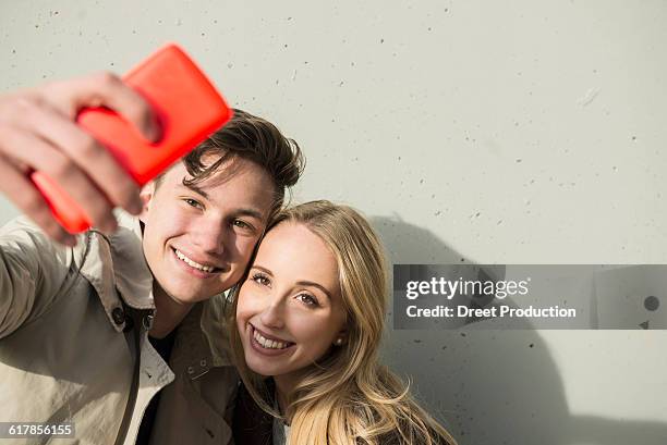 "young couple taking a selfie with smart phone, munich, bavaria, germany" - bavaria girl stockfoto's en -beelden