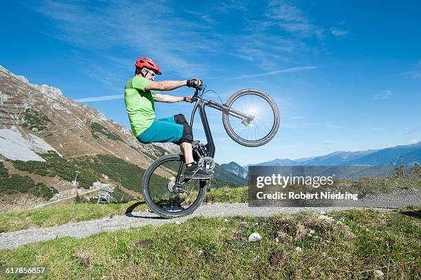 "mountain biker riding on back wheel through mountain, tirol, austria" - wheelie stock pictures, royalty-free photos & images