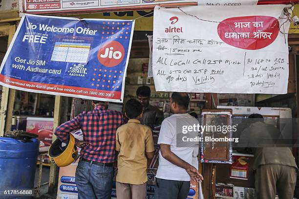 Banners for Reliance Jio, the mobile network of Reliance Industries Ltd., top left, and Bharti Airtel Ltd. Hang outside a mobile phone store in...