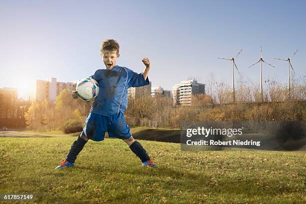 "dirty soccer player cheering on field and wind turbines with city in background, bavaria, germany" - breitbeinig stehen stock-fotos und bilder