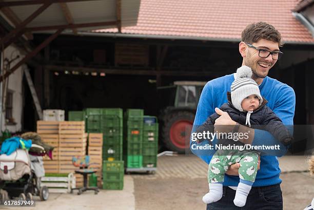 "mid adult man carrying his son and smiling, bavaria, germany" - baby winter farm son stock pictures, royalty-free photos & images