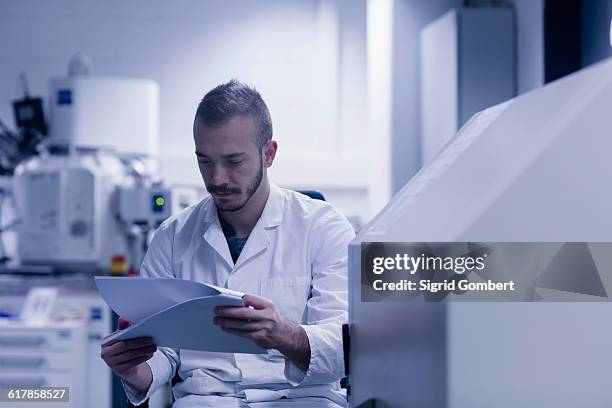 "young male scientist looking at report in an optical laboratory, freiburg im breisgau, baden-württemberg, germany" - laboratory report stock pictures, royalty-free photos & images