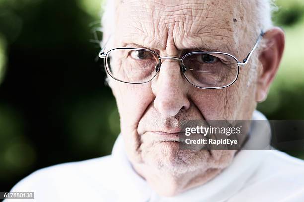 le vieil homme sévère jette un coup d’éclat sur ses lunettes: vieil homme grincheux - vieux grincheux photos et images de collection