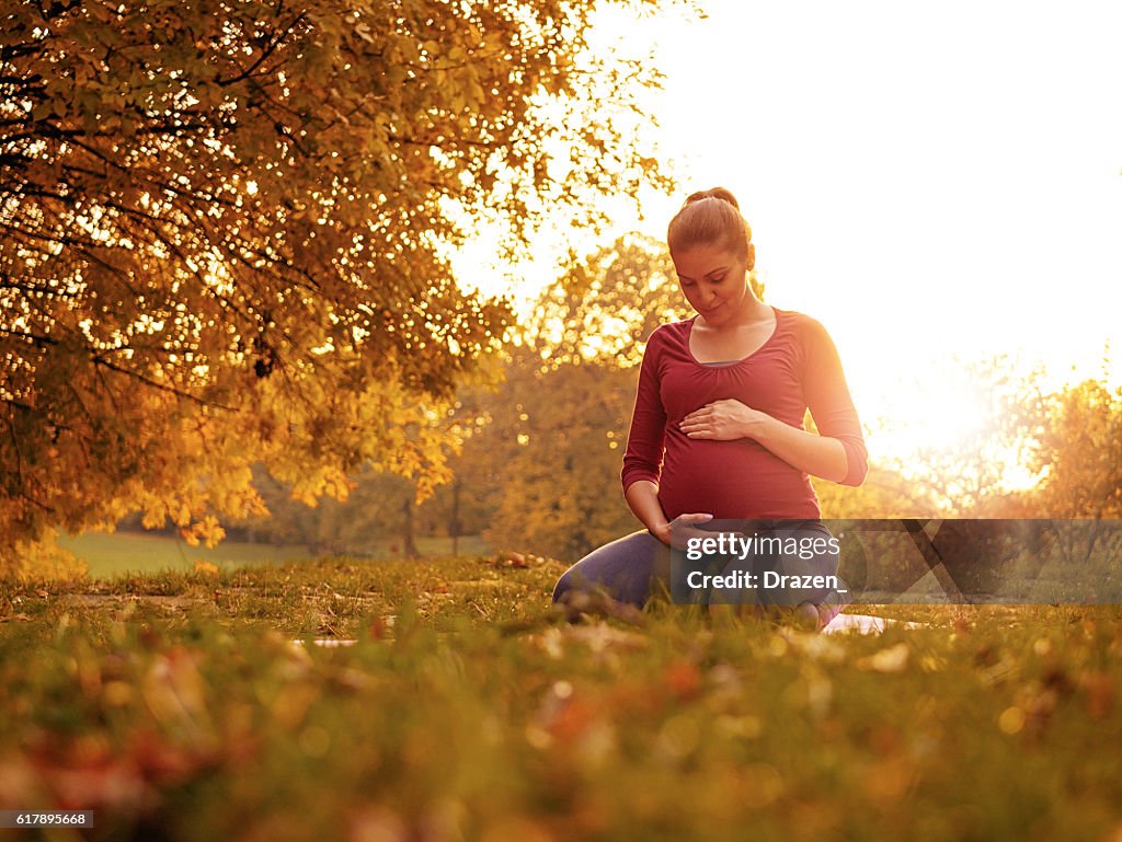 Happy pregnant woman in park