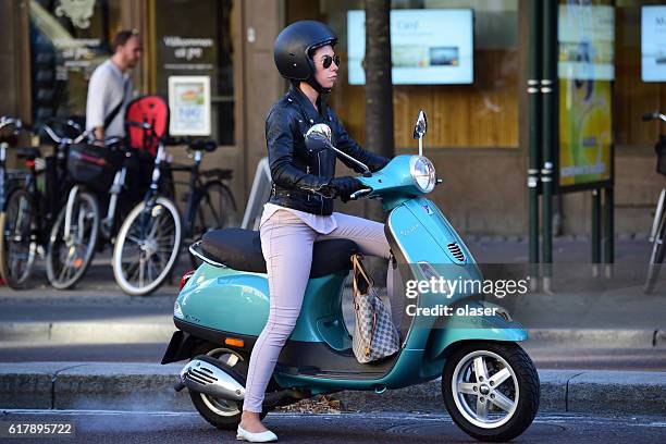 mujer bien vestida montando vespa en el centro de estocolmo - vespa brand name fotografías e imágenes de stock