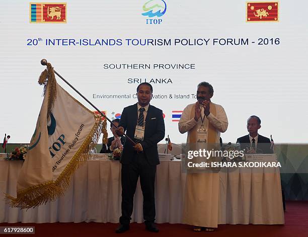 Sri Lankas Southern Province governor Hemakumara Nanayakkara receives a flag from organisers of a provincial board member -- Jerome Chirstan V....