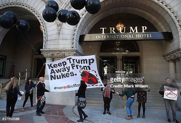 Anti-nuclear weapon activists raise a banner that reads "Keep Trump Away From Nukes" during a rally outside the Trump Hotel in Washington, DC. The...