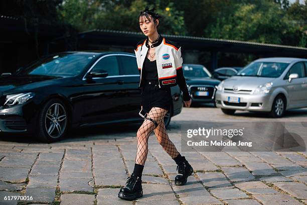 Korean model Sora Choi wears a cropped motocycle-style leather jacket, choker necklace, black top and shorts, fishnet tights, and chunky black boots...