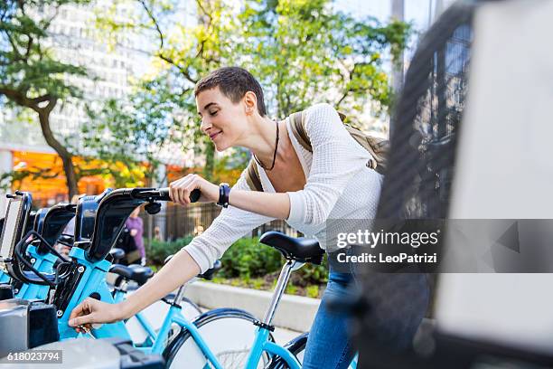 woman commuting to work by bicycle in the city - bike sharing stock pictures, royalty-free photos & images