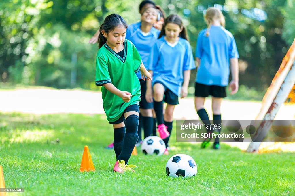Young female soccer player practices drills