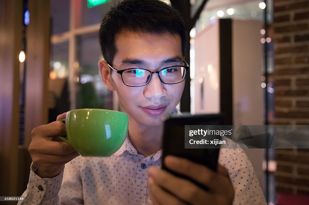 Man using phone,drinking a cup of coffee