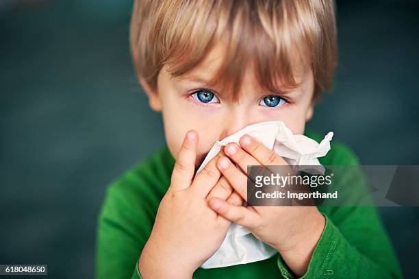 portrait of a sick boy cleaning his nose - verkoudheid en griep stockfoto's en -beelden