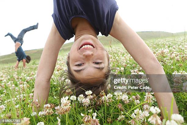 boy and girl doing handstands in field - fare la verticale sulle mani foto e immagini stock