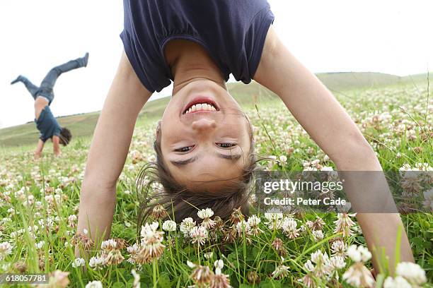 boy and girl doing handstands in field - upside down stock pictures, royalty-free photos & images