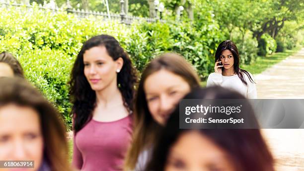 friends walking in a park and talking on the phone. - toxic friendship stock pictures, royalty-free photos & images