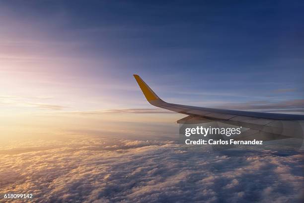 image of airplane flying over cloudy sky at sunset - ala de avión fotografías e imágenes de stock