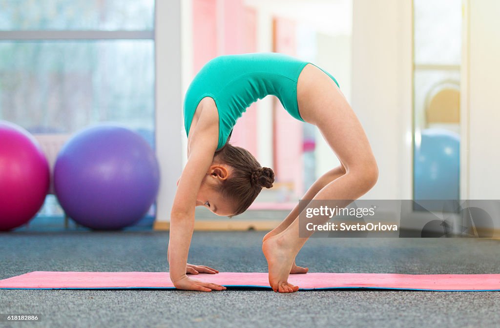 Flexible Little Girl Gymnast Doing A Bridge In Gym High-Res Stock Photo ...