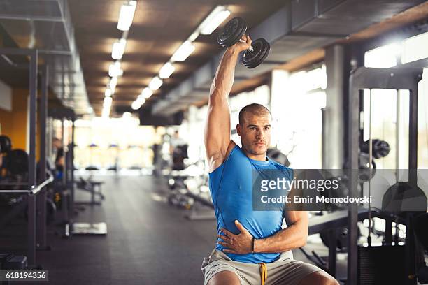 musculaire jeune homme en levant " haltères dans la salle de gym. - musculation des biceps photos et images de collection