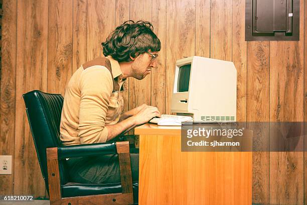 funny nerdy man looking intensely at vintage computer - humor stockfoto's en -beelden