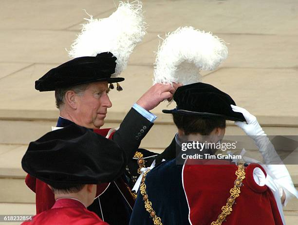 Prince Charles, the Prince of Wales, helps his sister Princess Anne, the Princess Royal, with her plumed hat at St George's Chapel for the...