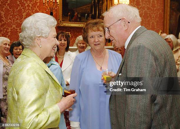 Queen Elizabeth II holding a glass of her favourite drink meets Allan Garrioch and his wife Helen at an 80th birthday lunch at home at Buckingham...