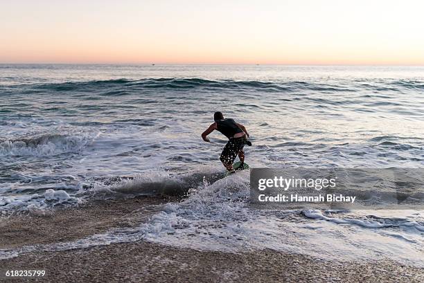 guy on a skim board in the sea/beach - hannah bichay stock pictures, royalty-free photos & images