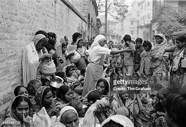 Nun helping mothers and children queuing for food aid at Mother Teresa's mission for the poor in Calcutta, India