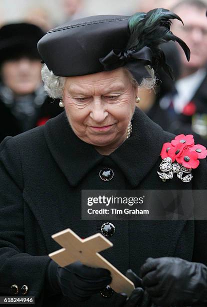 Queen Elizabeth II lays a cross for those that died fighting for Britain and its allies in conflict as she visits the Field of Remembrance at...