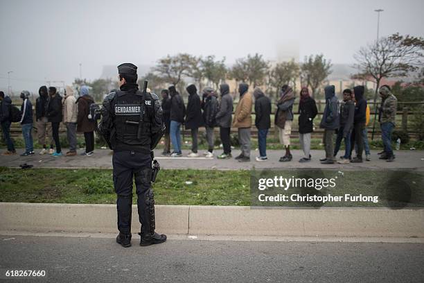 Migrants queue in the morning mist to board buses and leave the notorious Jungle camp as authorities demolish the site on October 26, 2016 in Calais,...