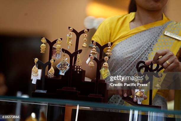 Saleswoman shows a gold earings to customers at a jewelry showroom. Diwali is India's biggest and most important holiday of the year. The festival...