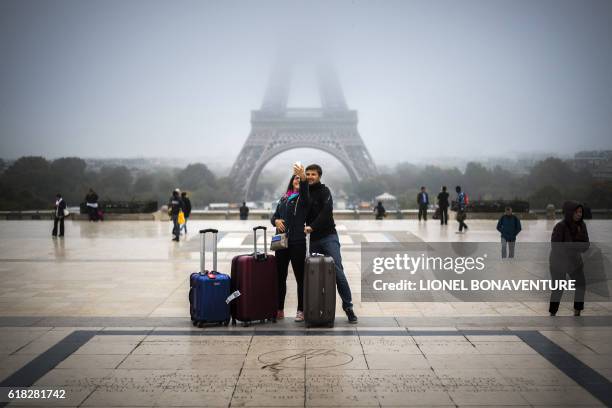 Tourists take a selfie on the Parvis des droits de l'homme square, in front of the Eiffel tower, on October 26, 2016 in Paris.