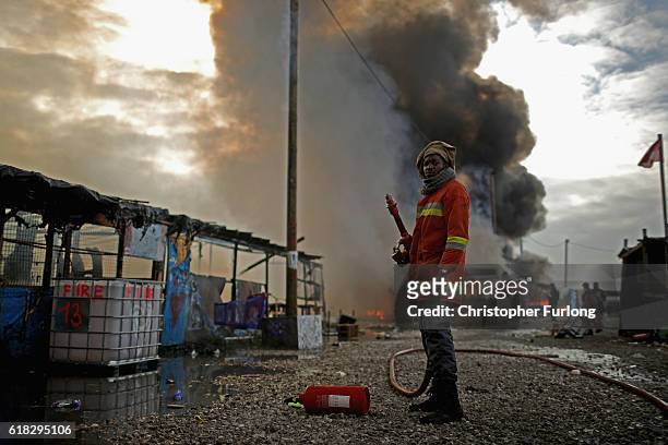 Volunteer tries to extinguish a fire in the notorius Jungle camp, believed to have been started by departing migrants, as authorities demolish the...