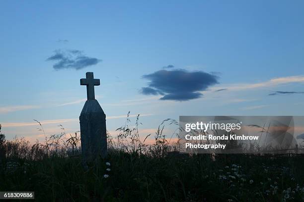 cross shaped tombstone at sunset - cemetery stock-fotos und bilder