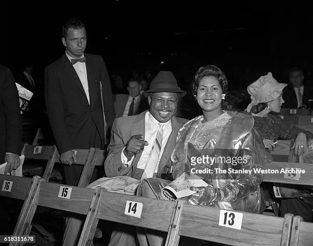 Archie Moore and his wife are one of the many spectators at the Carmen Basilio vs. Sugar Ray Robinson middleweight title fight in Bronx, New York,...