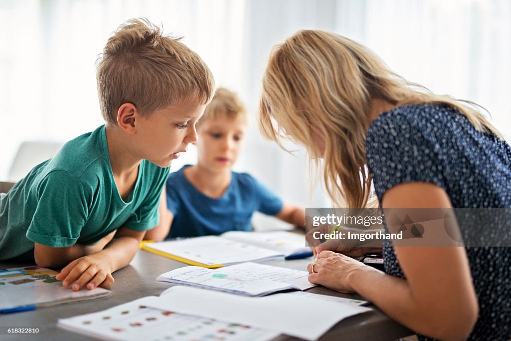 Mother doing homework with her sons.