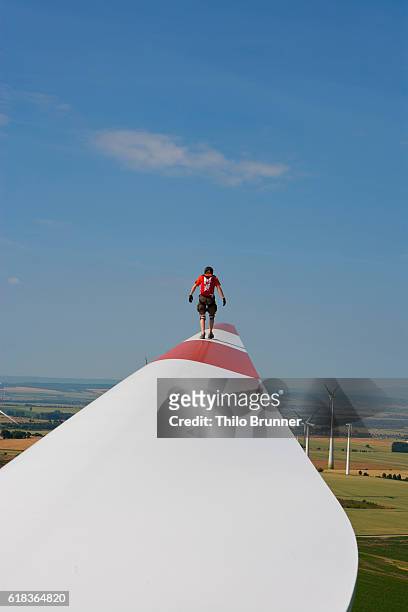 young man walking on wind turbine wing - wingwalking stock pictures, royalty-free photos & images