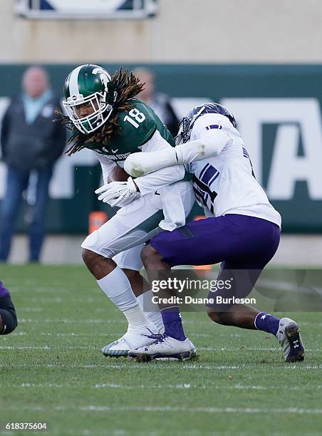 Wide receiver Felton Davis III of the Michigan State Spartans is tackled by safety Kyle Queiro of the Northwestern Wildcats during the second half at...