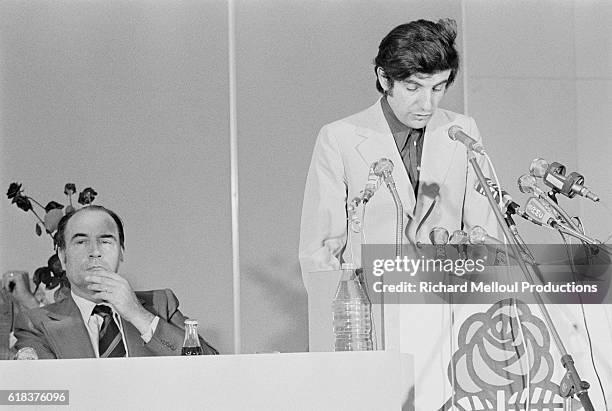 French politician Jean-Pierre Chevenement gives a speech during the 1974 Socialist Party national meeting as party leader Francois Mitterrand listens...