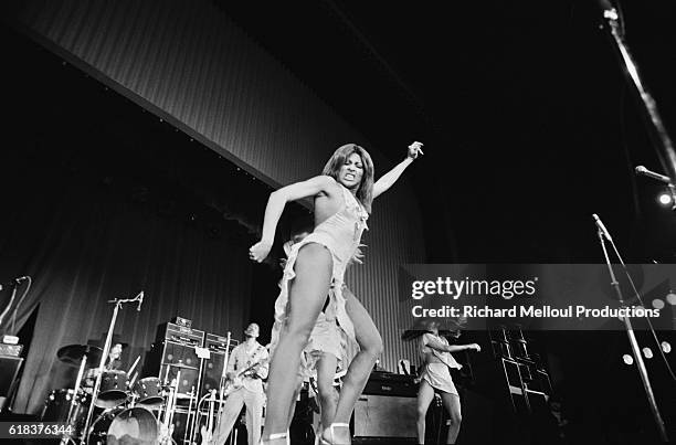 Tina Turner dances on stage during a 1975 concert at the Olympia in Paris. In the background on guitar is her husband Ike.