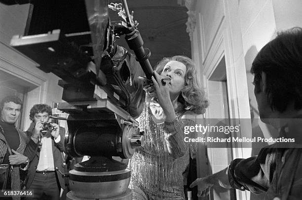 French actress and director Jeanne Moreau stands with a camera on the set of the 1976 film Lumiere, a romance movie which she is both directing and...