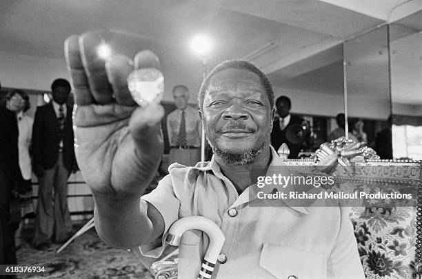 Jean-Bedel Bokassa holds up a large jewel. Bokassa became president of the Central African Republic through a military coup, and later declared...