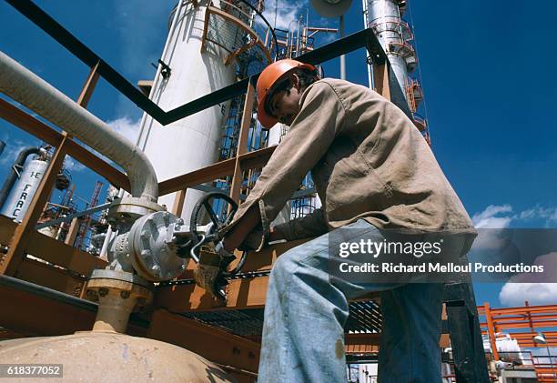 Petroleum worker turning a pipeline wheel at the Pemex oil refinery in Mexico. Pemex is Mexico's national oil refinery.